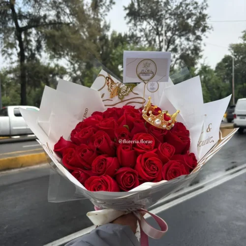 Ramo de rosas rojas con corona decorativa y envoltura elegante de Florería Florae.