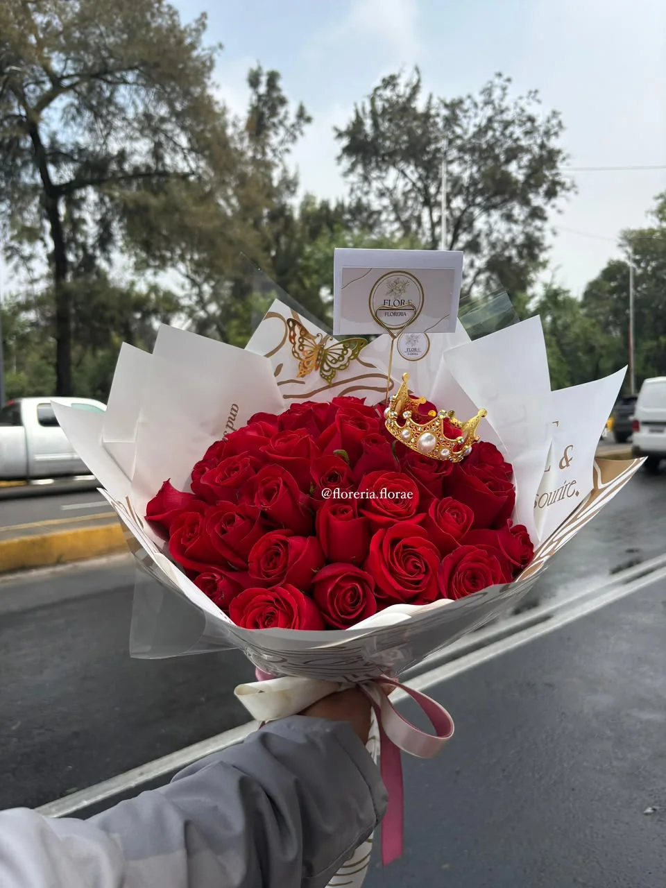 Ramo de rosas rojas con corona decorativa y envoltura elegante de Florería Florae.