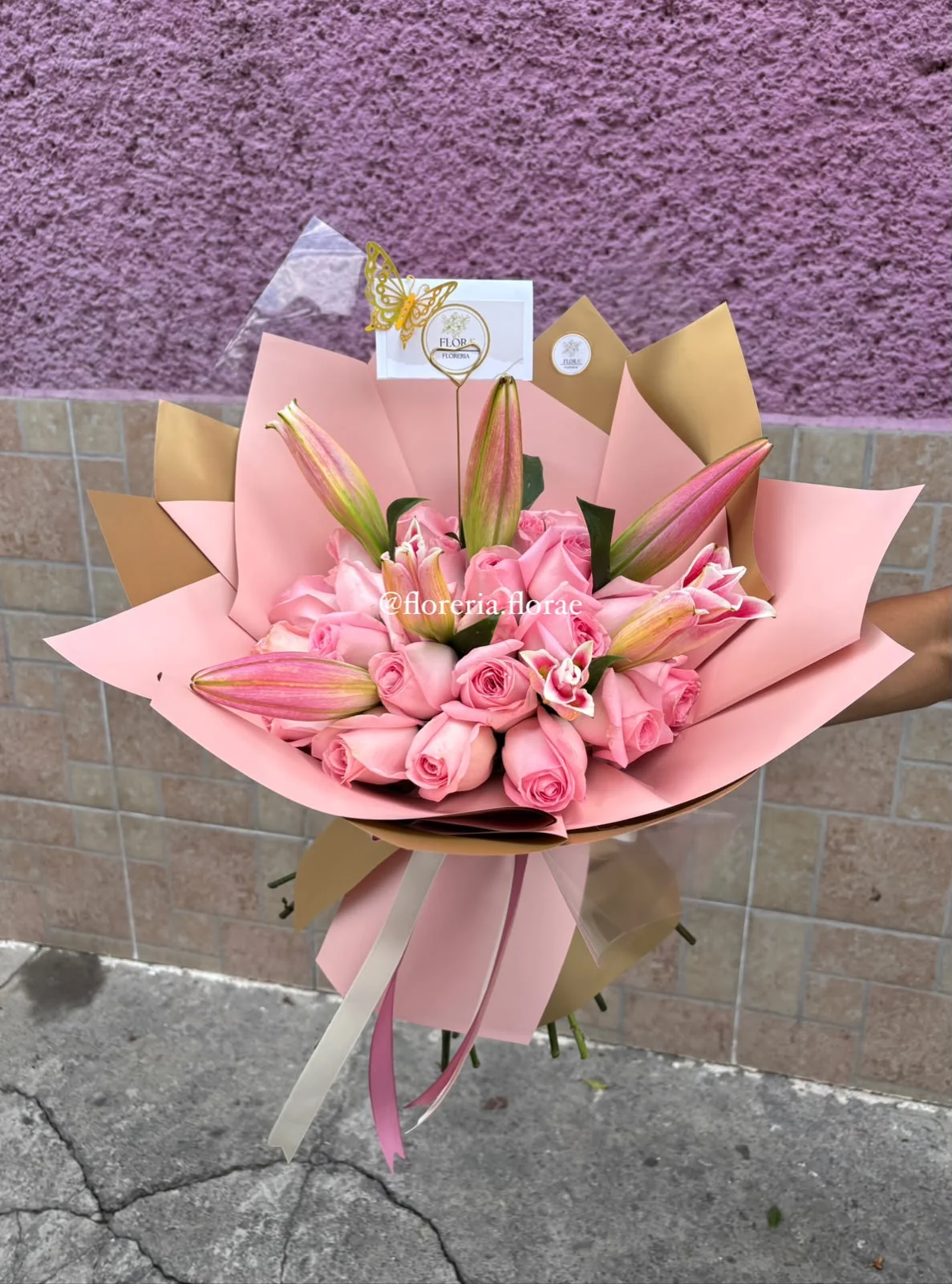 Ramo de rosas rosadas y lirios con envoltura rosa y dorada de Florería Florae.