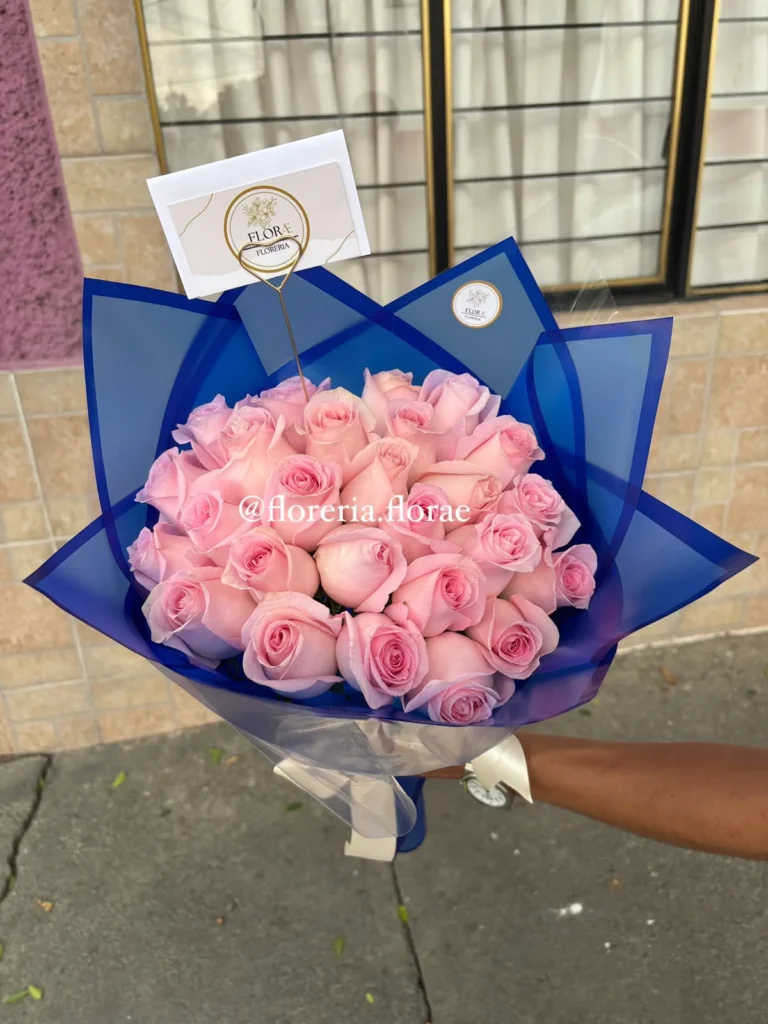 Bouquet de rosas rosadas envuelto en papel azul elegante, regalo romántico moderno de Florería Florae.