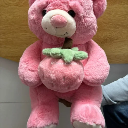 Peluche de oso rosa abrazando una fresa suave para regalo.