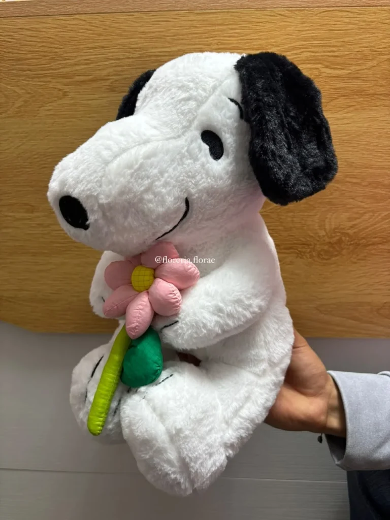 Peluche de Snoopy sosteniendo una flor rosa para regalo tierno.