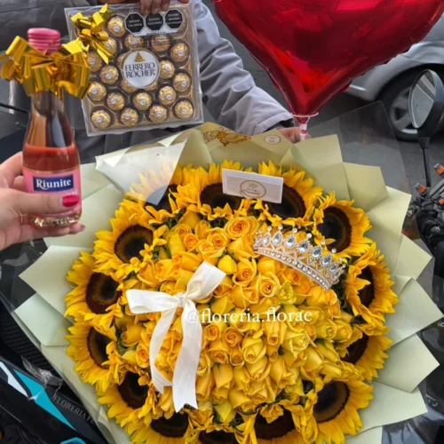Ramo buchón gigante de 100 rosas amarillas rodeado de girasoles con tiara brillante, globo de corazón rojo, botella de mini vino Riunite y caja de Ferrero Rocher.