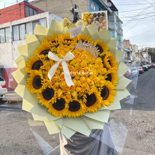 Ramo buchón gigante de 100 rosas amarillas rodeado de girasoles con tiara brillante, globo de corazón rojo, botella de mini vino Riunite y caja de Ferrero Rocher.